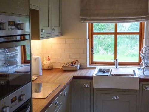a kitchen with a sink and a stove and a window at Stable Cottage in Withernwick