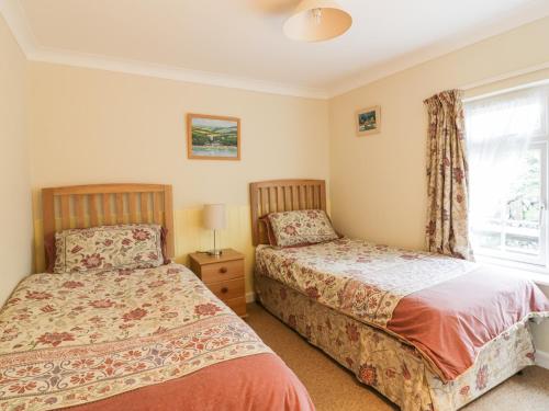 two beds in a bedroom with a window at Polurrian in Helston