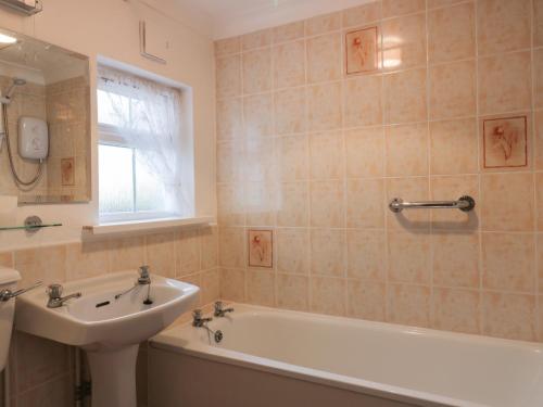 een badkamer met een wastafel, een bad en een wastafel bij Polurrian in Helston
