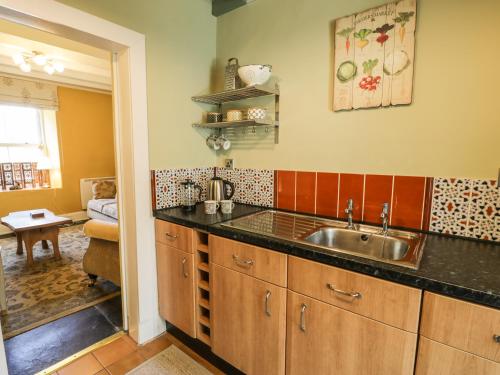 a kitchen with a sink and a living room at Miners Cottage in Blaenau-Ffestiniog