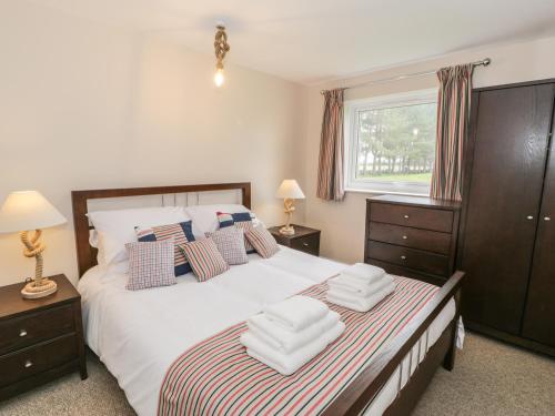 a bedroom with a large white bed with two chairs at Driftwood in Harlech