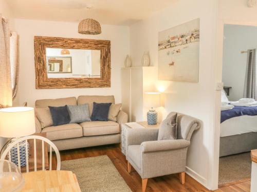 a living room with a couch and a chair and a bed at Wren Cottage in Ilfracombe