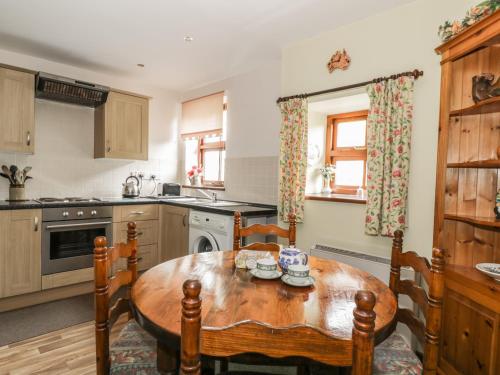 a kitchen with a wooden table and chairs in it at Gardeners Cottage in Hesket Newmarket