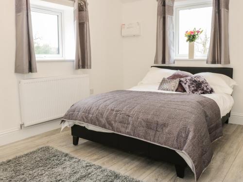 a bedroom with a bed and two windows at Hoden View in Cleeve Prior