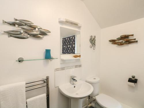 een badkamer met een wastafel, een toilet en een spiegel bij Westcliff in Penzance
