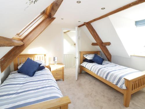 two beds in a room with wooden beams at Avalon in Stonehouse