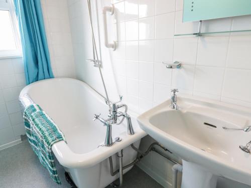 a bathroom with a sink and a bath tub at Daisy Cottage in Perranporth