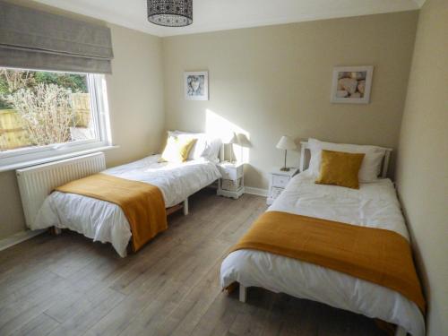 1 dormitorio con 2 camas y ventana en Oakdene en Milford Haven