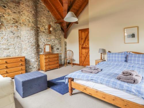 a bedroom with a bed and a stone wall at Swallows Cottage in Luppitt