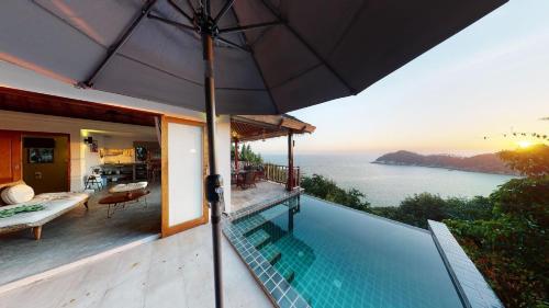 a house with a swimming pool and an umbrella at The Fisherman's Villas in Koh Tao