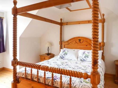 a wooden canopy bed with a wooden frame in a bedroom at Bonnie Doon in Kilfearagh
