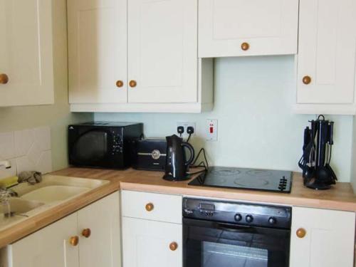 a kitchen with white cabinets and a black stove top oven at The Beach House Apartment in Buncrana