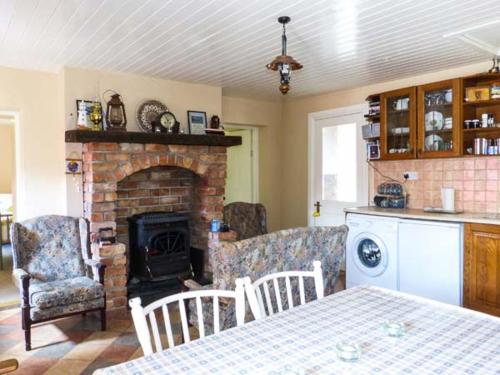 a living room with a fireplace and a table and chairs at Ferrys in Portsalon