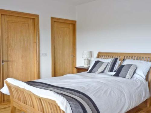 a bedroom with a large white bed with blue pillows at Cúnna Bán in Derreen