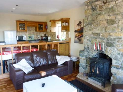 a living room with a couch and a stone fireplace at Ti Sheamuis in Clifden
