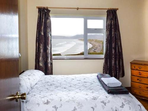 a bedroom with a bed and a window with a view at Rossbeigh Beach Cottage No 6 in Rossbeigh