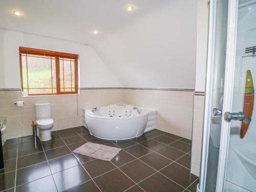 a bathroom with a white tub and a toilet at Mulroy View in Burnfoot