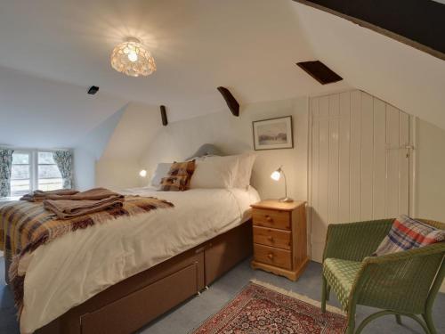 LewdownにあるLew Quarry Cottageのベッドルーム(大型ベッド1台、椅子付)