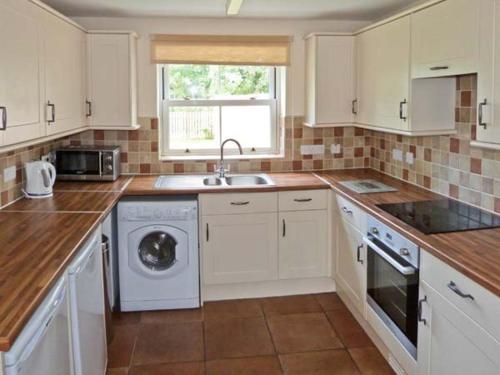 a kitchen with white cabinets and a washing machine at Summer Farm Cottage in Bedale