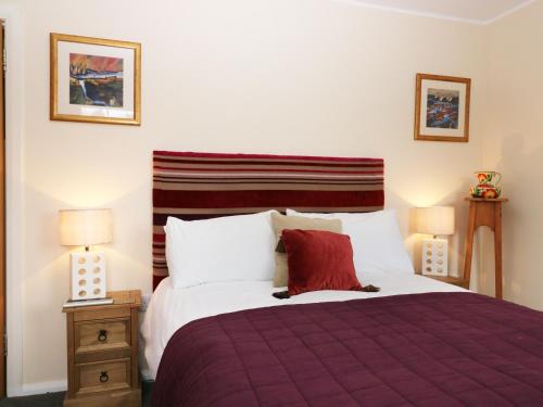a bedroom with a bed with a purple blanket and two lamps at Torgorm in Glenelg