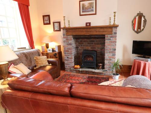 a living room with a leather couch and a fireplace at The Old Chapel in Chesterfield