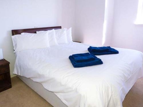 a white bed with two blue towels on it at The Clamshell in Isle of Whithorn