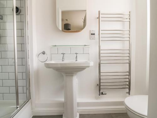 La salle de bains blanche est pourvue d'un lavabo et d'un miroir. dans l'établissement Ivy Cottage, à Colchester