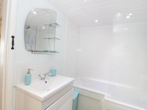 uma casa de banho branca com um lavatório e um espelho em The Hideaway em Benllech