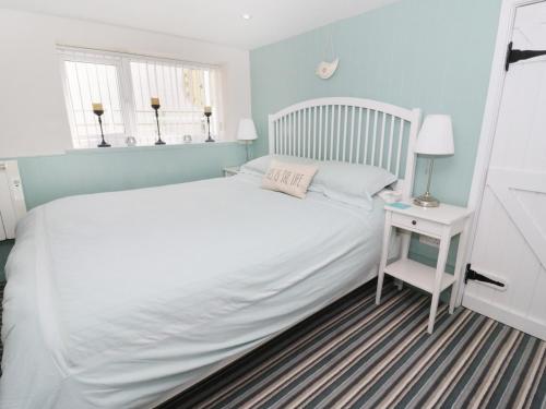 - une chambre avec un lit blanc et une table de chevet blanche dans l'établissement The Hideaway, à Benllech