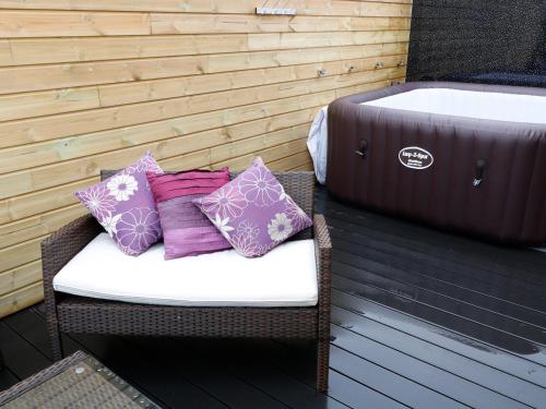 a wicker chair with three pillows on a patio at Northlands Country Cottage With Hot Tub in Plymouth