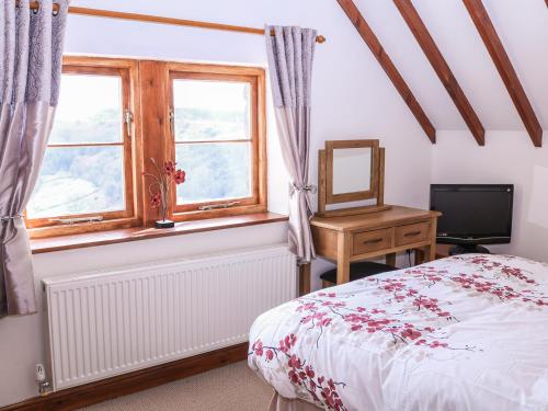 a bedroom with a bed and a desk and a window at Shire Cottage at Top Butterley Farm in Tansley