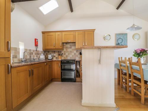 a kitchen with wooden cabinets and a stove top oven at Skiddaw in Cockermouth