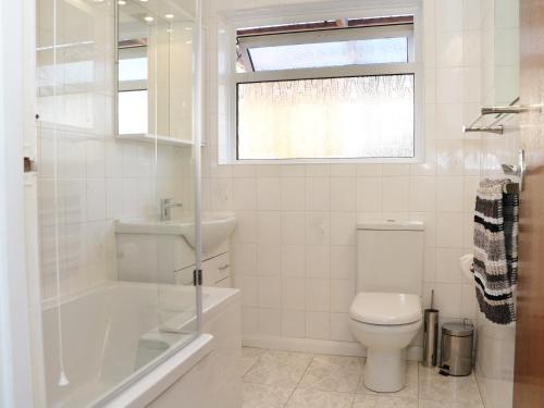 a white bathroom with a toilet and a sink at Sengador in Christchurch