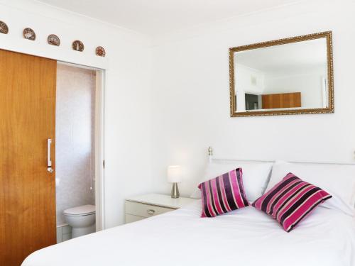 a white bed with two striped pillows and a mirror at Sengador in Christchurch