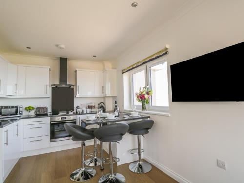a kitchen with white cabinets and a flat screen tv at 24 Waters Edge in Banff