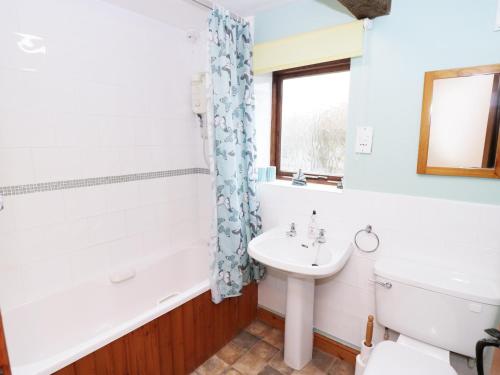 a bathroom with a tub and a sink and a toilet at Meadow Cottage in Great Edston