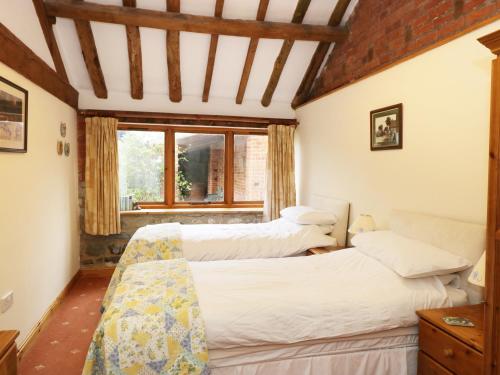 two beds in a room with a window at Sunset Cottage in Great Edston
