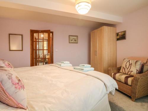 a bedroom with a large white bed and a chair at Peonies in Exmouth