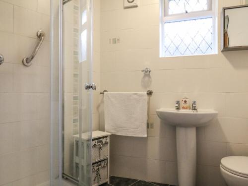 a white bathroom with a sink and a shower at Peonies in Exmouth