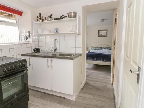 a kitchen with white cabinets and a sink and a bed at The Nest in Llangollen