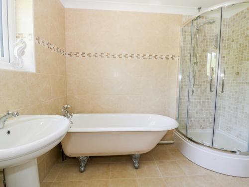 ein Badezimmer mit Badewanne, Waschbecken und Dusche in der Unterkunft Orchard Cottage in Holywell