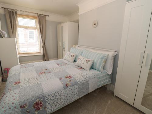 a bedroom with a bed with a quilt on it at Salee Cottage in Newbiggin-by-the-Sea