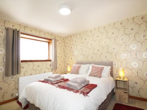 a bedroom with a large white bed with a window at Dalnahaven in Grantown on Spey