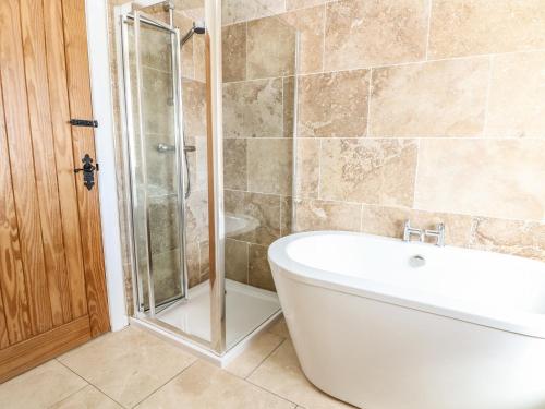a bathroom with a tub and a glass shower at Bryn Uchaf in Benllech