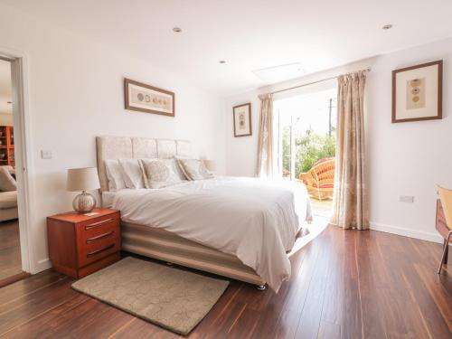 a white bedroom with a bed and a window at Chy Lagen Hos in Newquay