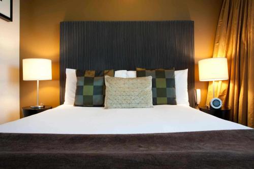 a bedroom with a large bed with two lamps at The Quadrant Hotel & Suites in Auckland