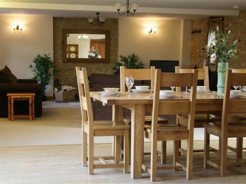 a wooden table with chairs and a dining room at Tithe Barn, Lyneham in Bruern