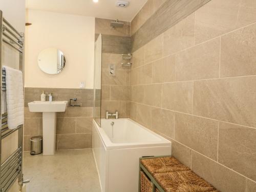 a bathroom with a white tub and a sink at Bull Cottage in Burford