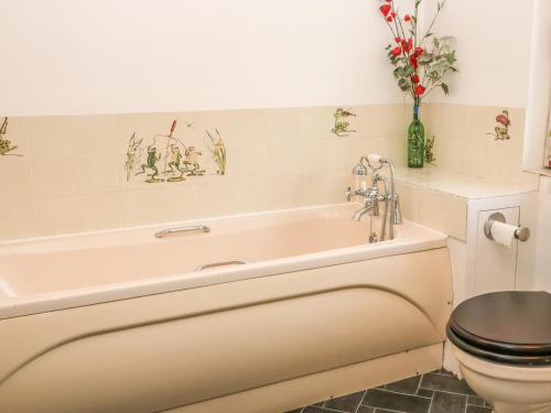 a bathroom with a bath tub and a toilet at Wadham Cottage in Bourton on the Water