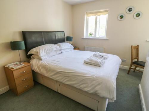 a bedroom with a bed with white sheets and a window at Bramble Cottage in Sedbergh